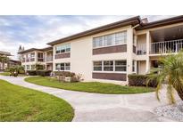 Well maintained two-story condo building featuring tan stucco walls, brown accents, and lush, landscaped surroundings at 4712 Marine Pkwy # 104, New Port Richey, FL 34652