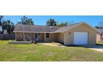 Charming single-story home featuring a stone accent wall and attached garage on a sunny day at 8528 Viva Via Dr, Hudson, FL 34667