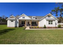 Inviting modern farmhouse with a well-manicured lawn and charming front porch, perfect for relaxed outdoor living at 10489 Florida Wren Ave, Weeki Wachee, FL 34614