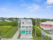 Two story home with light pink paint, teal doors, and a cozy front porch at 3251 Shoal Line Blvd, Hernando Beach, FL 34607
