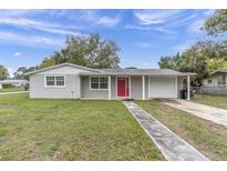 Charming single story home featuring a well maintained lawn and welcoming red front door at 7037 Green St, New Port Richey, FL 34652