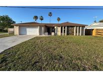 Charming single-story home featuring a two-car garage, stone accents, and a spacious front yard with palm trees at 8607 Longboat Ln, Hudson, FL 34667