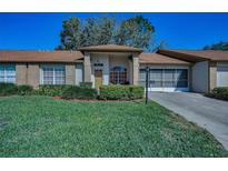 Charming single-story home featuring a well-manicured lawn and a cozy front porch with attractive landscaping at 9713 Sweeping View Dr, New Port Richey, FL 34655