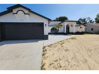 Charming single-story home with a gray and white exterior, well-maintained landscaping and a spacious driveway at 1032 Concert Ave, Spring Hill, FL 34609