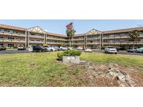 English Tudor condo building featuring well-maintained landscaping, ample parking and an American flag on a sunny day at 2464 Australia E Way # 46, Clearwater, FL 33763
