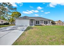 Charming single-story home featuring a well-maintained lawn, attached two-car garage, and long private drive at 7205 Pinehurst Dr, Spring Hill, FL 34606