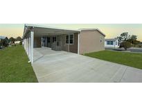 Tan home exterior with a covered carport, grassy lawn, and a concrete driveway at 9896 Scepter Ave, Brooksville, FL 34613