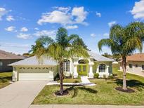 Charming one-story home with a two-car garage, bright yellow front door and palm trees at 10285 Velvetseed Cir, Spring Hill, FL 34608