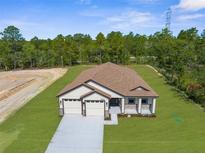 New construction home with a three car garage, craftsman-style details, and a well maintained lawn at 16043 Penn State Rd, Weeki Wachee, FL 34614