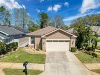 Inviting single-Gathering home featuring a well-maintained lawn, two-car garage, and neutral stucco facade at 3555 Sylvan Edge Dr, Palm Harbor, FL 34685