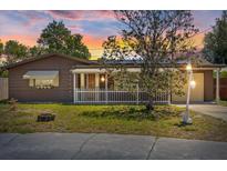 Charming single-story home featuring brown siding, a cozy front porch, and a well-maintained lawn at sunset at 3728 Linkwood St, New Port Richey, FL 34652