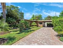 Charming single-story home with a brick driveway, lush landscaping, and an inviting carport at 6433 Murray Hill Dr, Tampa, FL 33615