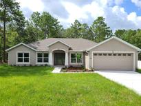 Charming single-story home with a well-manicured lawn, complemented by lush trees and a two-car garage at 11192 Kodiak Wren Rd, Weeki Wachee, FL 34614