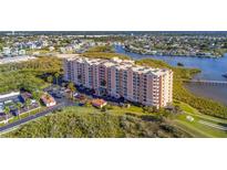 An aerial view of a pink waterfront condominium building with lovely landscaping and views of the bay at 4516 Seagull Dr # 408, New Port Richey, FL 34652