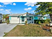 Charming home featuring a colorful exterior, white garage door, and well-manicured landscaping at 13906 Barnard Ave, Hudson, FL 34667