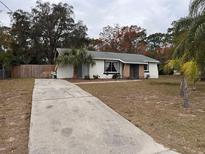 Charming single-story home with a long driveway and mature landscaping on a sunny day at 5249 Courtland Rd, Spring Hill, FL 34608