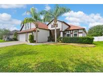 Well-maintained two-story home with lush green lawn and tropical landscaping creating curb appeal at 5737 Wynstone Ln, Zephyrhills, FL 33541