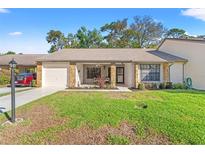 Charming single-story home featuring a well-manicured lawn and a cozy front porch with stone accents at 6652 Brambleleaf Dr, Spring Hill, FL 34606