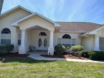 Charming single-story home featuring a beautiful front entrance with white columns and a well-manicured lawn at 8630 Ne Coral Creek Loop, Hudson, FL 34667