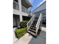 Exterior stairwell featuring white railings and mature landscaping at 9485 Hamlin Blvd # 8, Seminole, FL 33776