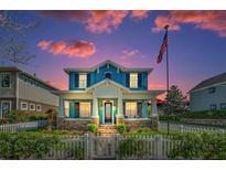 Charming blue two-story home with stone accents, a white picket fence and a manicured front yard at 10623 Marsha Dr, New Port Richey, FL 34655