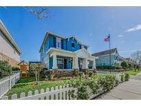 Charming two-story blue home with a welcoming front porch, lovely landscaping, and a white picket fence at 10623 Marsha Dr, New Port Richey, FL 34655