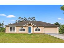 Charming home featuring a blue front door, neutral siding, attached garage and well-maintained lawn at 1313 Gatewood Ave, Spring Hill, FL 34608