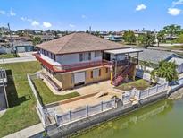 Two-story waterfront home featuring a backyard patio, fenced yard and expansive balconies on the upper level at 13820 Plumosa Ave, Hudson, FL 34667