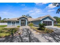 Charming single story home features a lovely blue exterior and well maintained front yard with mature landscaping and lovely walkway at 15193 Copeland Way, Brooksville, FL 34604