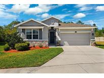 Charming single-Gathering home with a two-car garage, stone accents, lush landscaping, and a well-manicured lawn at 15793 Midnight Dove Ct, Odessa, FL 33556