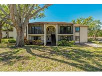 Two-story condo complex featuring balconies, mature landscaping and a large shade tree at 1737 Pine Ridge W Way # B-1, Palm Harbor, FL 34684
