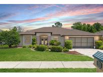 Charming single-story home featuring a manicured lawn, brick accents, and a two-car garage at 1038 Greenturf Rd, Spring Hill, FL 34608