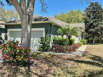 Charming home featuring a well-maintained lawn, mature trees, and a two-car garage at 13648 Crest Lake Dr, Hudson, FL 34669