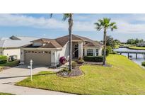 Charming single-story home with a well-manicured lawn, lush landscaping, and two-car garage located waterfront at 1809 Westerham Loop, Trinity, FL 34655