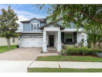Charming two-story home with a landscaped front yard, covered entryway, and brick-paved driveway leading to a two-car garage at 2596 Whittler Br, Odessa, FL 33556