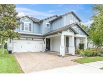 Charming two-story home with a light blue exterior, a brick driveway, and a two-car garage at 2596 Whittler Br, Odessa, FL 33556