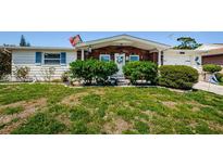 Charming home with brick accents, complemented by a well-manicured front yard, shrubs, and a vibrant flag at 4107 Glissade Dr, New Port Richey, FL 34652