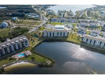 Aerial view of waterfront community featuring multiple buildings, a pool, a lake, and a beautiful landscape at 8251 Brent St # 918, Port Richey, FL 34668