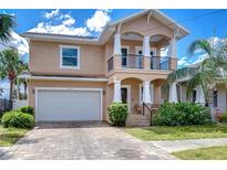 Inviting two-story home features a front balcony, brick paver driveway, and lush landscaping at 2506 W Ivy St, Tampa, FL 33607