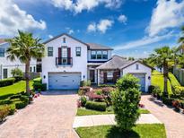 Beautiful two-story home with a three car garage, a brick driveway, and lush landscaping at 2630 Milford Berry Ln, Tampa, FL 33618