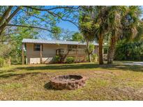 Inviting home exterior with metal roof, fire pit, and lush landscaping on a sunny day at 7240 Creek Dr, New Port Richey, FL 34655