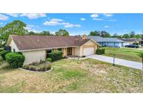 Single-story home features a well-manicured lawn and attached two car garage on a sunny day at 11256 Holbrook St, Spring Hill, FL 34609