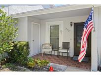Inviting front porch with chairs, brick flooring, and an American flag at 12505 Dearborn Dr # C, Hudson, FL 34667