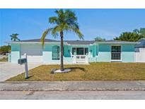 Charming one-story home featuring a well-maintained yard, light blue exterior, and a palm tree in the front at 7221 Westwind Dr, Port Richey, FL 34668