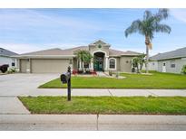Charming single-story home featuring lush landscaping, palm trees, and a welcoming facade at 7511 Melogold Cir, Land O Lakes, FL 34637