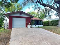 Charming home with a red brick facade, attached garage, and a screened-in porch at 10619 Mira Vista Dr, Port Richey, FL 34668