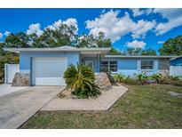 Beautiful single-story home with a garage, blue exterior, stone accents and lush front yard at 1074 Woodbrook S Dr, Largo, FL 33770