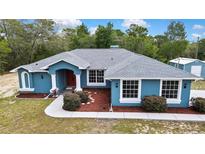 Charming single Gathering home featuring a vibrant blue exterior, landscaped yard, and a welcoming front entrance at 11379 Flower Ave, Weeki Wachee, FL 34613