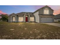 Charming home featuring stucco exterior, arched entryway, attached garage, and well-maintained front yard at 3017 Aldoro Ave, Spring Hill, FL 34609