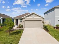 Charming single-story home featuring a well-manicured lawn and an attached two-car garage at 30839 Penny Surf Loop, Wesley Chapel, FL 33545